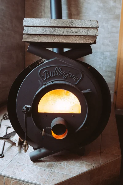 Schwarzer Bullerjan Holzofen mit brennendem Feuer, bereit für gemütliche Wärme. Ideal für Unternehmen, die professionelle Imagefotos und Imagevideos suchen.