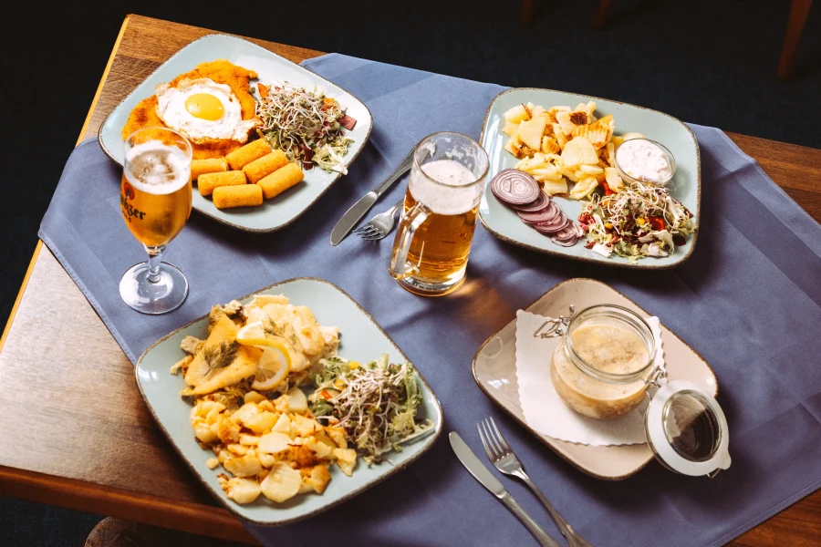 Professionelle Unternehmensfotografie: Ein gedeckter Tisch mit deftigen deutschen Gerichten, Bier und Beilagen, perfekt für Imagefotos und Imagevideos von einem erfahrenen Fotografen und Imagevideografen.