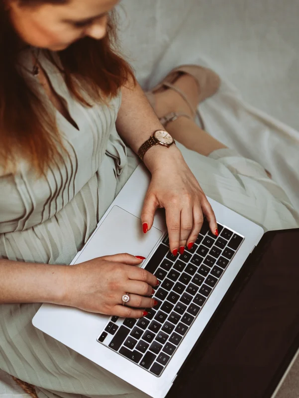 Frau mit rotem Nagellack tippt auf Laptoptastatur