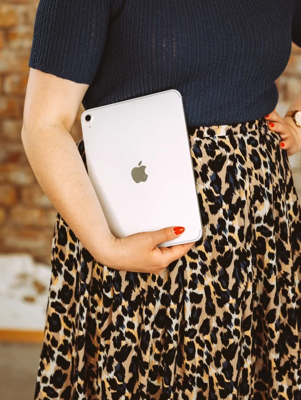 Frau mit Leopardrock hält ein silbernes iPad